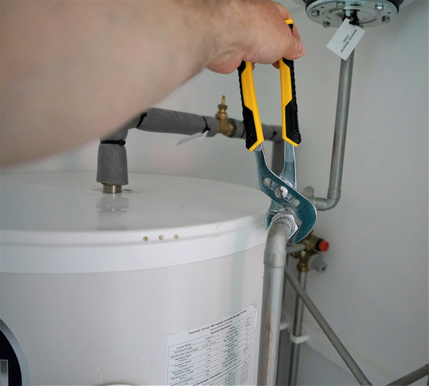 Plumber's hand servicing a hot water heater with a wrench